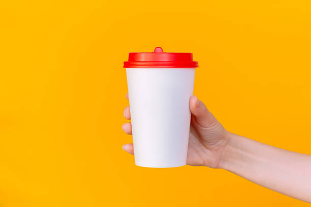 istock A woman's hand holding a white paper coffee cup with a red lid. Empty space. 2196000717