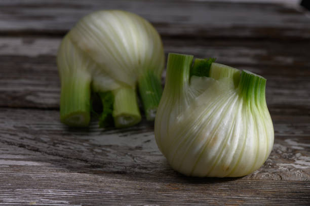 Sliced green onions showcase their vibrant green tops and layered white bulbs, resting on a weathered wooden table.