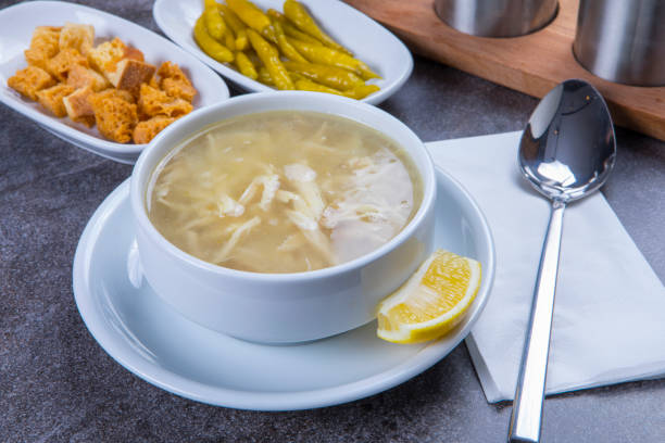With its warm and nourishing qualities, chicken soup reaches new heights of flavor when paired with lemon, pickled pepper, and crispy bread pieces. This classic dish offers a light yet satisfying experience, balancing tangy, spicy, and crunchy textures perfectly. Ideal for cold days or those seeking a wholesome meal, this comforting soup stands out with its appetizing presentation and rich aroma. A visually stunning choice for restaurant menus, gourmet content, and food photography, this traditional favorite delights both the palate and the eyes.