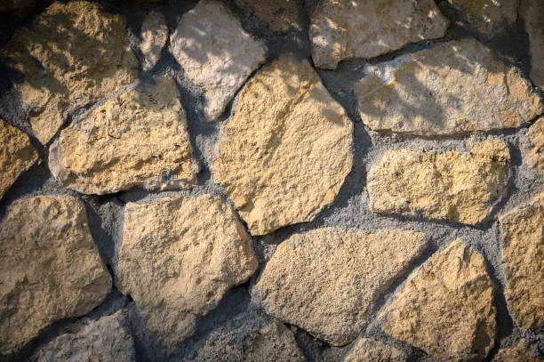 istock Natural sunlight casts gentle shadows on a rustic stone wall in a serene outdoor setting 2196001889
