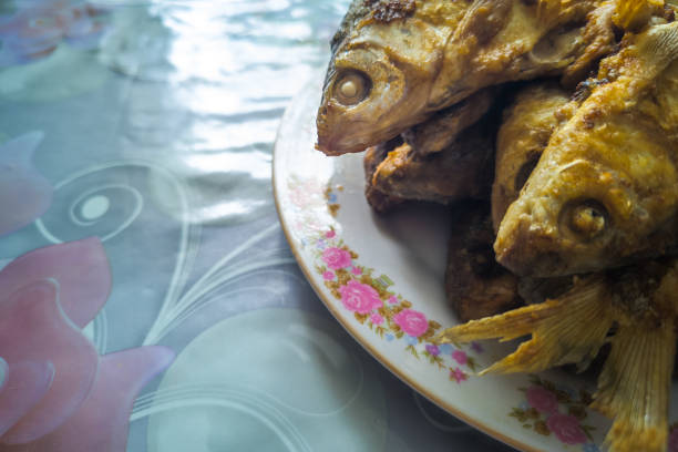 whole fried in batter freshwater fish on a plate over rustic oilcloth covered table, closeup