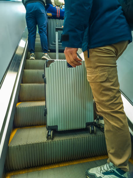istock Traveler with Rolling Suitcase on a escalator 2196004740