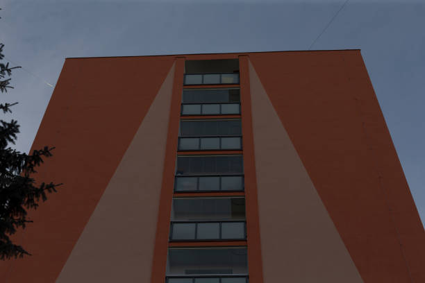 The image shows a tall apartment building against a cloudy backdrop, showcasing its impressive design