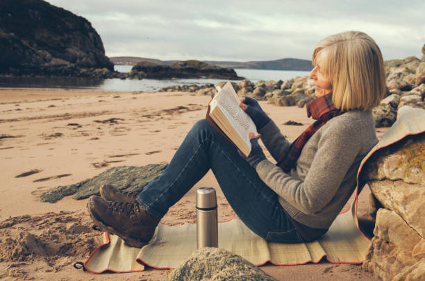 Reading on holidays. Coffee cup and book on chair outdoors against blue sea water background.