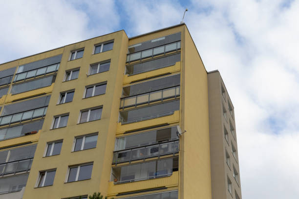 A tall yellow apartment building stands against a bright blue sky