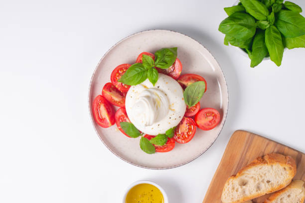 istock Delicious Italian caprese salad with sliced mozzarella, tomatoes, basil, and bread on background. 2196010902
