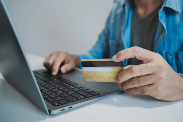 istock Man holding credit card while using laptop, shopping online, buying on internet 2196012388
