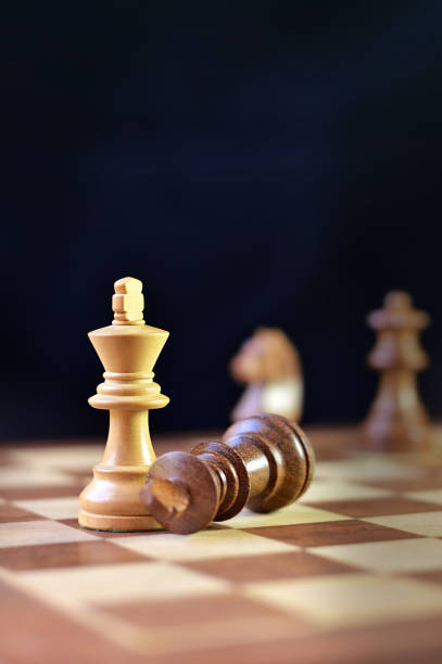 istock Last move in chess, check mate, victory, brown king chess piece fallen down defeated, against black background, more chess pieces defocused in backdrop 2196013208
