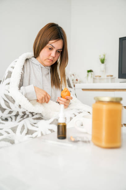 istock A sick girl is peeling and eating a tangerine 2196015050