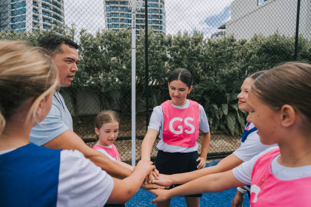 istock Australian young netball team players huddling stacking hands before the game start with coach 2196019410