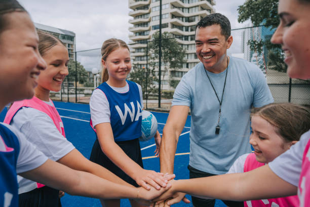 istock Australian young netball team players huddling stacking hands before the game start with coach 2196019417