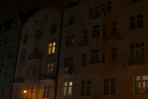 A breathtaking night view of a modern urban building, showcasing its brilliantly lit windows that accentuate its unique architectural details amidst a vibrant, bustling city environment