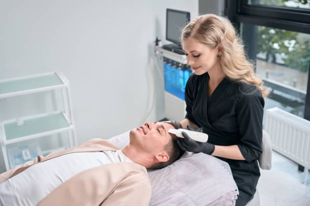 istock Woman cosmetologist using ultrasonic scrubber to remove impurities from client skin 2196030056