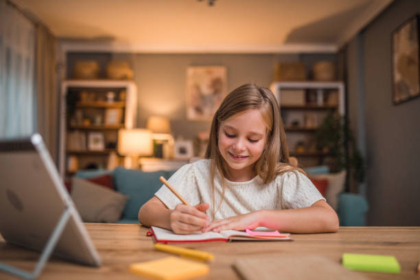 istock A gorgeous little girl uses both a digital tablet and a notebook while writing and studying at home 2196031332
