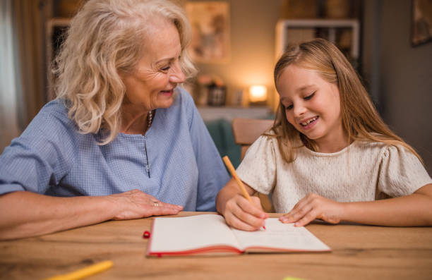 istock A smiling grandmother helps her granddaughter while she studies and does her homework 2196032354