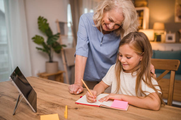 istock A smiling grandmother helps her granddaughter while she studies and writes her homework 2196032392