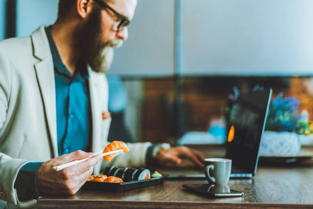 istock Businessman eating sushi in the office 2196033065