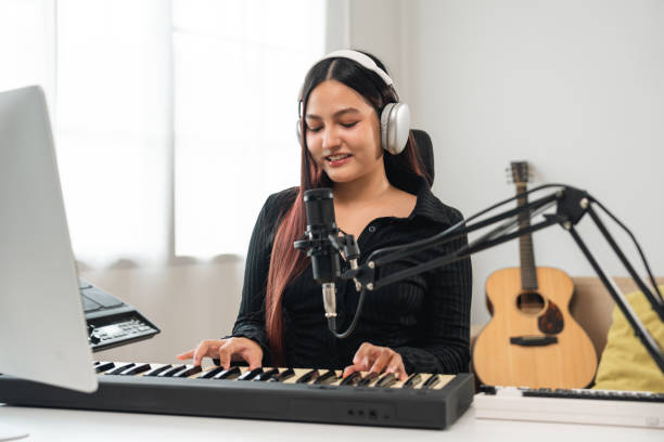 istock Professional Musician with condenser microphone and tablet for Mixing Mastering music. Music composer woman composing a song with guitar and piano keyboard at digital Recording home studio 2196034507
