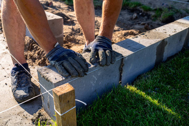 istock A man lays concrete blocks on a poured foundation, gluing them with mortar. 2196035736