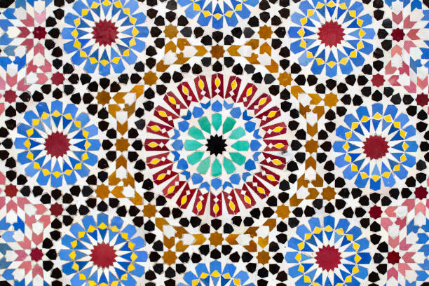 Casablanca, Morocco â Close-up of a colorful traditional Moroccan zellige mosaic tile pattern featuring geometric shapes in blue, green, brown, and white. The intricate Islamic design showcases Moroccan craftsmanship and architectural artistry often seen in mosques, palaces, and riads across the country.