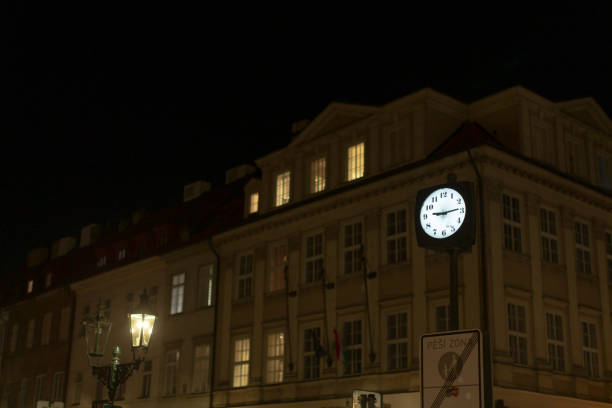 The clock on the historic building glows at night, with its illuminated windows enhancing the urban atmosphere, showcasing intricate architectural details and celebrating the citys culture