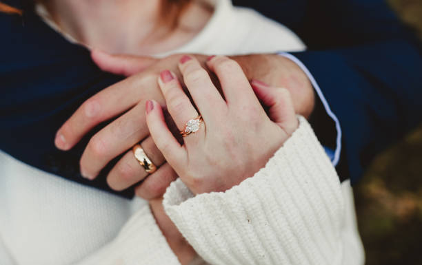 istock Newly engaged married couple embracing with focus on wedding rings 2196039180