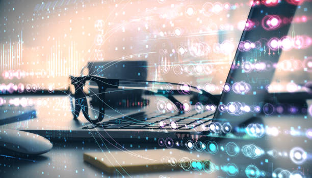 istock Abstract digital overlay of holographic data visuals with a laptop, glasses, and coffee cup on a desk in office setting. 2196039238
