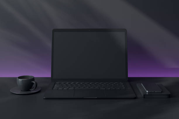 istock Blank laptop screen on desk with coffee cup and smartphone in modern dark setting. 3D Rendering 2196039922