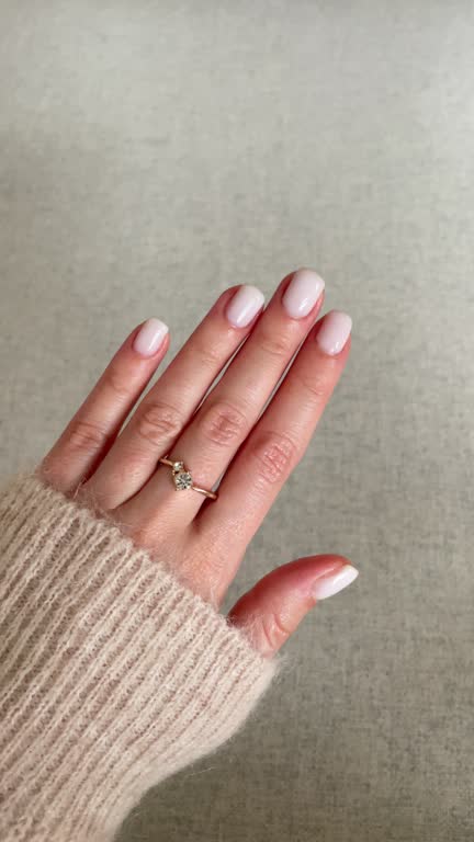 Woman's hand with white nail polish and a diamond ring