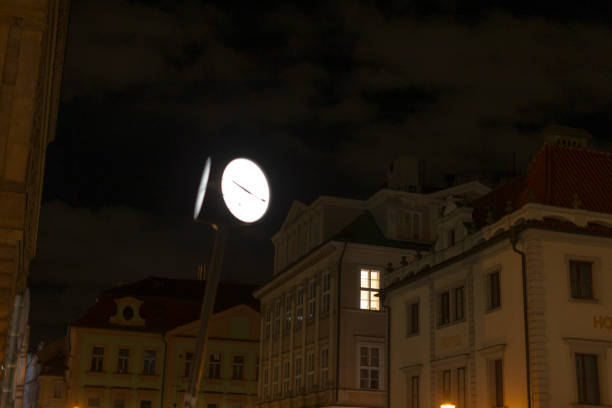 A captivating urban landscape showcases a clock mounted on a pole, surrounded by impressive buildings against the backdrop of a starry night sky, creating a vibrant city scene