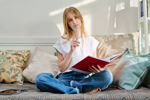 istock Portrait of female student sitting on couch with notebook, studying at home 2196041876