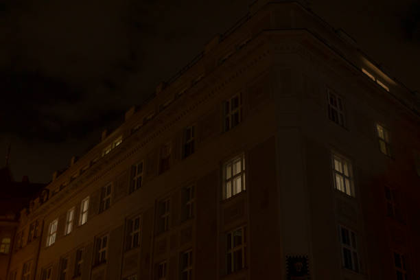 A large building featuring many windows is prominently illuminated during the nighttime hours, creating a striking visual effect against the darkness