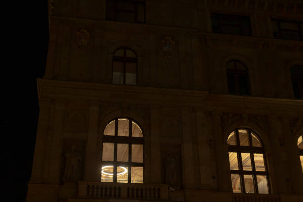 The nighttime view showcases a historic building, with its beautifully illuminated windows and intricate architectural details contributing to the citys charming atmosphere and character