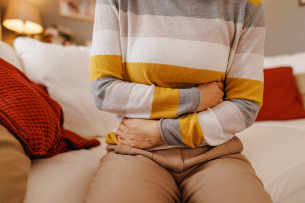 istock Woman experiencing abdominal pain while sitting on sofa at home 2196048699