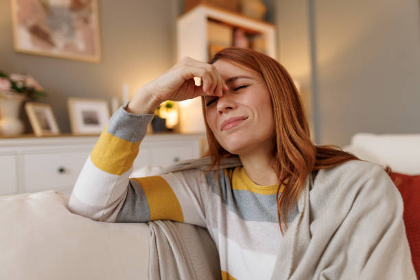 istock Woman suffering from sinus pain while sitting on sofa at home 2196049095