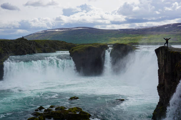 istock Person Standing On Cliff By A Waterfall In Iceland 2196051635
