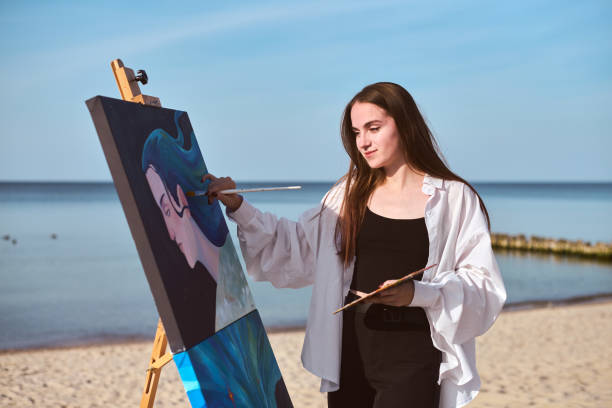 istock Young female painter creating art by seashore 2196051928