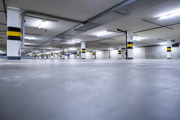 istock Modern, clean parking garage with bright neon lights and concrete floor with marked parking spaces. 2196051971