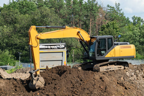 istock excavator loading soil into dump truck from construction site near forest 2196052785