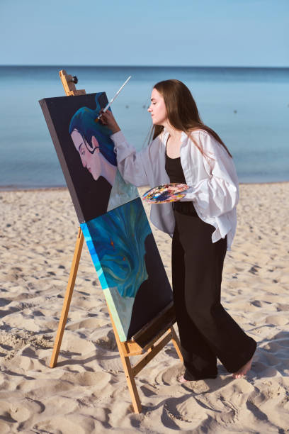 istock Young female painter creating art by seashore 2196052817