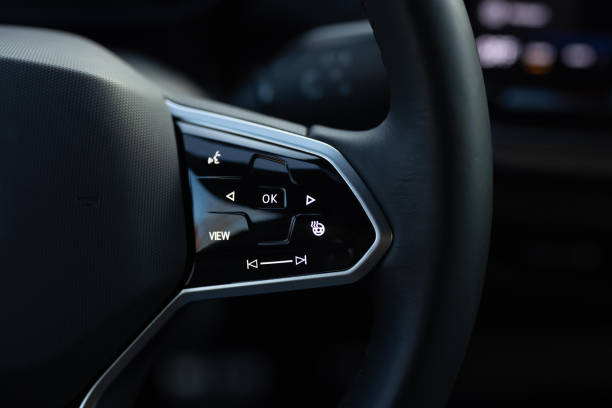 Heated steering wheel control buttons with blurred dashboard in car interior. Heated steering wheel switch. Steering wheel heating control panel.