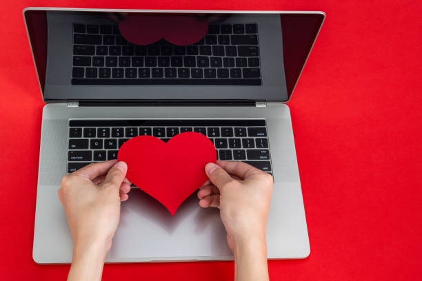istock Human hand holding red heart on the computer keyboard 2196056412