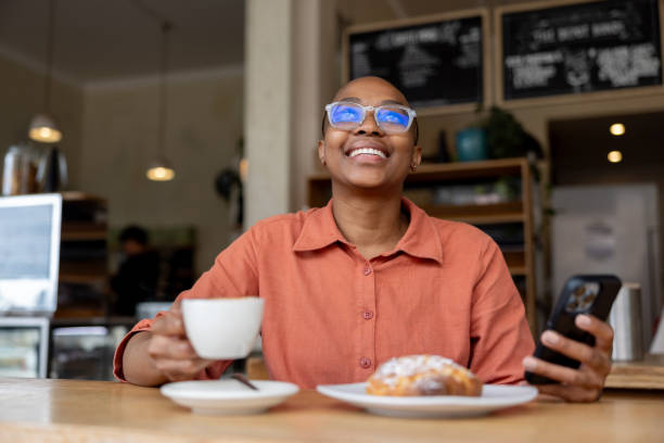 istock Woman having coffee and a pastry at a cafe while using her cell phone 2196056501