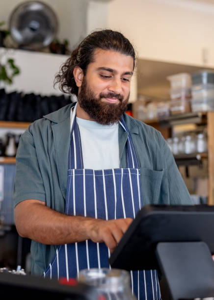 istock Waiter working at the cash register in a cafe 2196056528