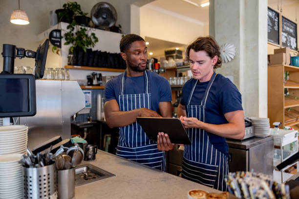 istock Barista training a new employee at a coffee shop and using a digital tablet 2196056548