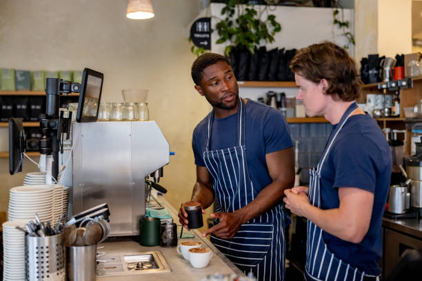 Barista teaching a new employee how to make coffee at a cafe