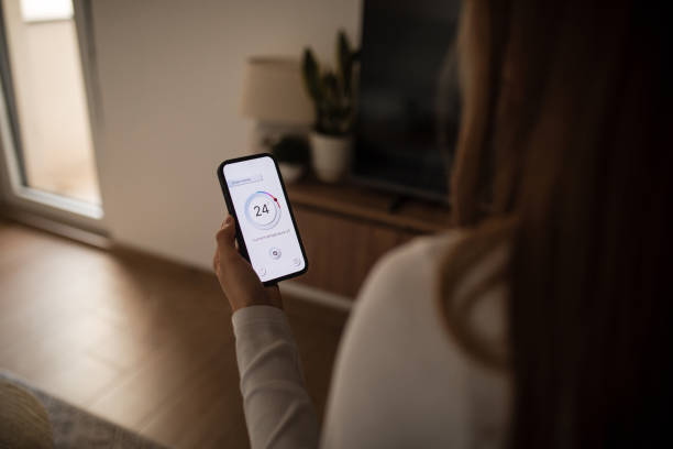 istock Woman using mobile phone to control termostat at home 2196059442