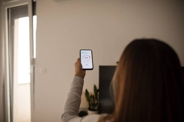 istock Woman using mobile phone to control termostat at home 2196059447