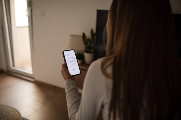 istock Woman using mobile phone to control termostat at home 2196059465