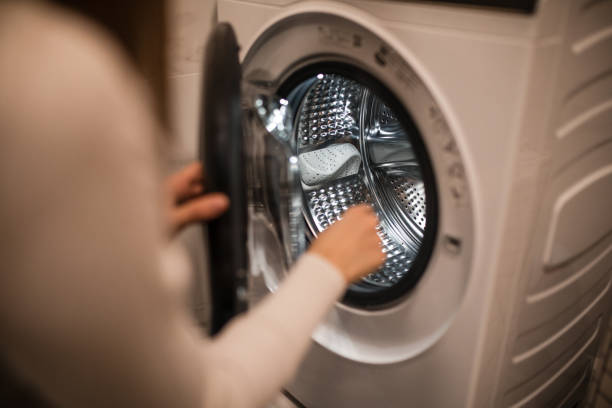 istock Young woman using washing machine at home 2196059623